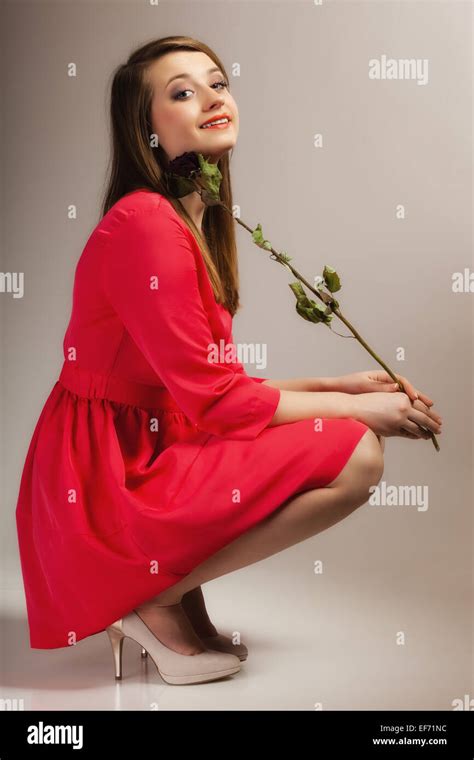 Beautiful Fashion Woman In Full Length Teen Girl In Red Gown With Dry Rose On Gray Background