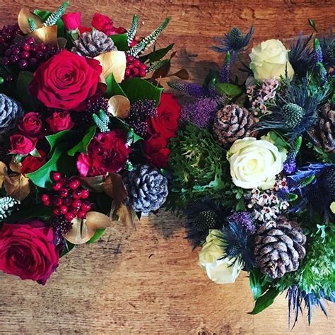 Two Bouquets Of Flowers Sitting On Top Of A Wooden Table Next To Each Other