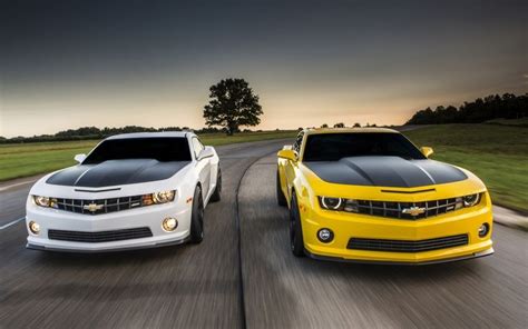 Two Chevrolet Camaros Driving Down The Road