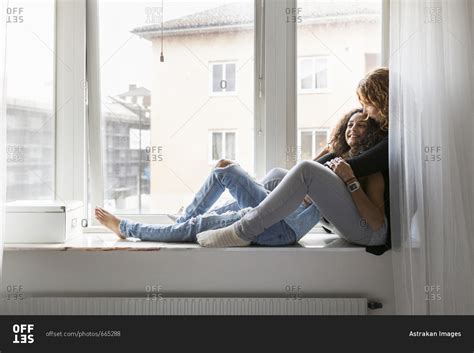 Two Women Sitting On Window Sill Stock Photo Offset