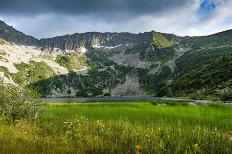 Lake At Foot Of Mountain Range River In Mountain Valley Along Rocks