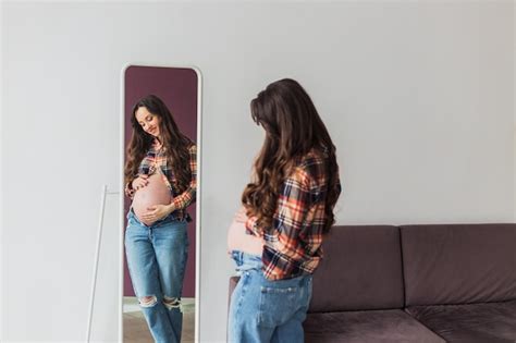 Premium Photo Pregnant Woman Looking At Herself In The Mirror Young