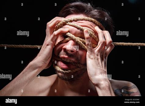Image Of Binded Brunette Man Trying Tear The Rope On Face Stock Photo