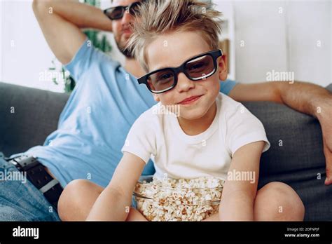 Father And Son Watching Movies At Home In 3d Glasses And Eating Popcorn