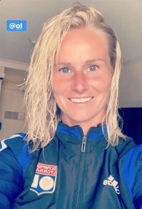 A Woman With Blonde Hair Wearing A Blue Jacket And Smiling At The