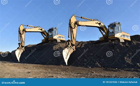 Excavators Working At Construction Site Backhoe Digs Ground In Sand Quarry On Blue Sky