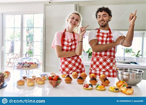 Couple Of Wife And Husband Cooking Pastries At The Kitchen With A Big Smile On Face Pointing