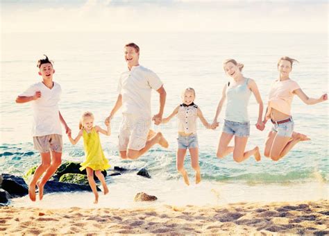 Grande Famille Sautant Ensemble Sur La Plage Par Beau Temps Photo Stock