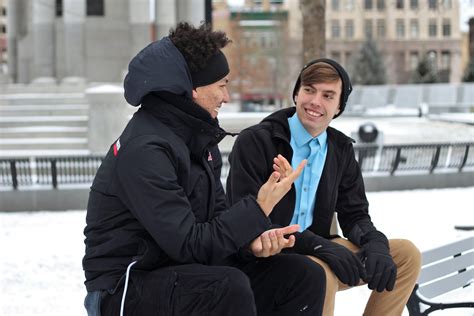 Two Guys Talking To Each Other While Sitting On A Bench In A Snowy Park