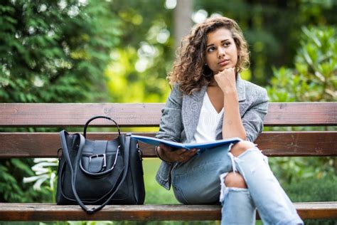 A Menina Que Senta Se Em Um Banco Lendo Um Livro Foto De Stock