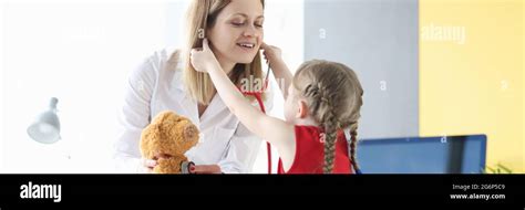 Little girl putting stethoscope on to doctor pediatrician in clinic ...