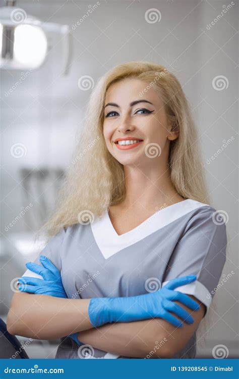 Portrait Of Female Dentist Smiling With Arms Crossed In Dental Clinic