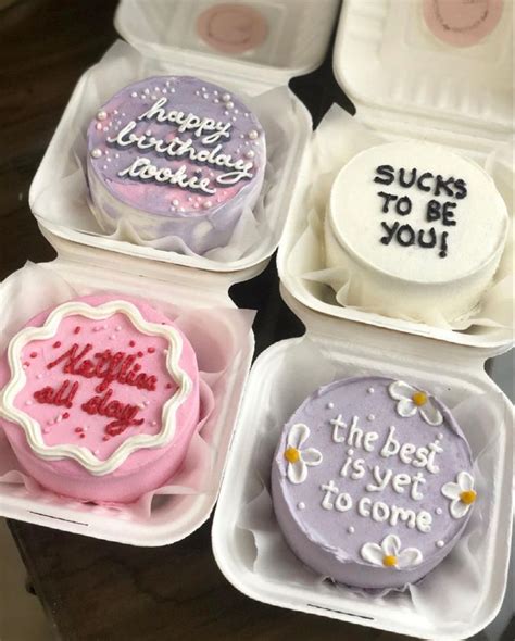 Four Decorated Cookies In Small Plastic Containers On Top Of A Wooden