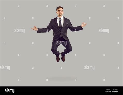 Calm young businessman in suit meditating, reaching zen and levitating ...