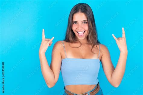 Beautiful Brunette Woman Wearing Blue Tank Top Over Blue Background