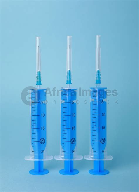 Disposable Syringes With Needles On Light Blue Background Stock Photo