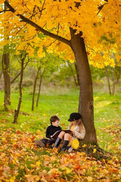 La Fille Et Le Garçon Sont Assis Sous Un Arbre Et Lisent Un Livre