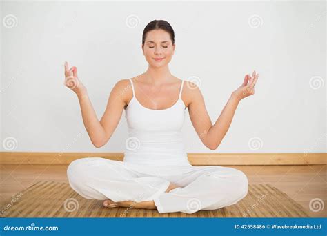 Smiling Brunette Sitting In Lotus Pose Looking At Camera Stock Photo