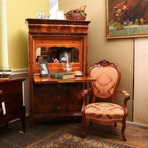 An Old Fashioned Desk With A Chair Next To It And A Painting On The Wall