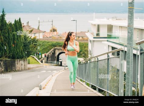 Portrait Of Young Beautiful Fit Woman Running Up The Hill Wearing