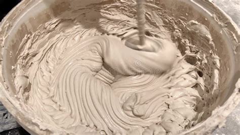 Worker Mixing Plaster Solution In A Bucket Using An Electric Drill