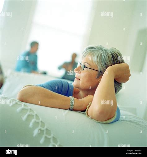 Mature Woman Sitting On Sofa People Sitting In Background Stock Photo Alamy