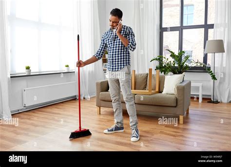 Man With Broom Cleaning And Calling On Smartphone Stock Photo Alamy