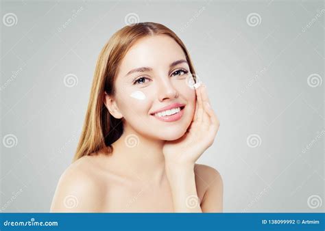 Beauty Portrait Of Cute Young Woman Smiling While Applying Some Facial