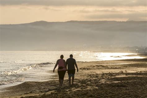 Couple Walking On The Beach At Sunrise Editorial Stock Image Image Of