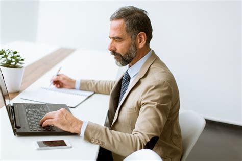 Premium Photo Mature Businessman In Classic Suit Using A Laptop While Working In His Office