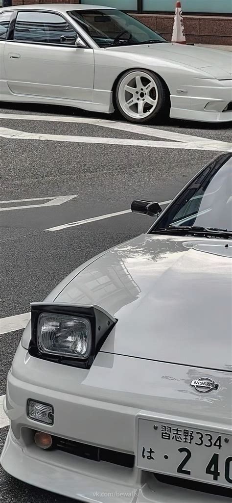 Two White Cars Parked Next To Each Other On A Street