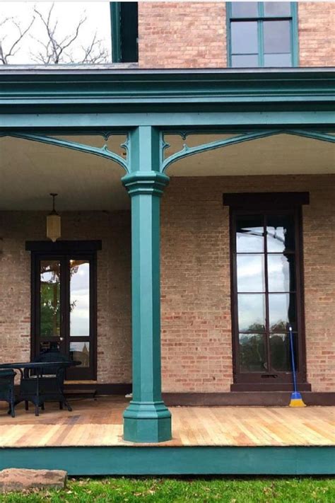 The Front Porch Is Covered With Green Columns