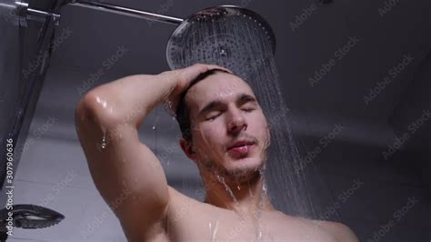 Young Handsome Man With Dark Hair Takes A Shower Like Rain Jets Of