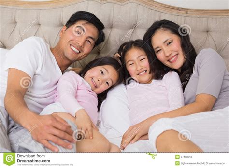 Retrato De Una Familia De Cuatro Miembros Feliz Que Miente En Cama Foto