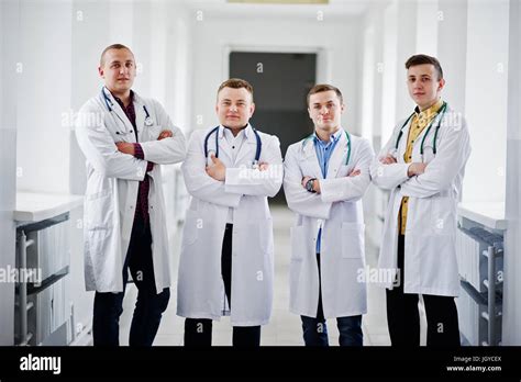 Four Confident Male Doctors In White Coats With Stethoscopes Standing