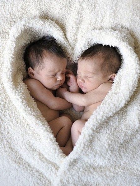 Two Newborn Babies Are Cuddling In A Heart Shaped Blanket On Top Of