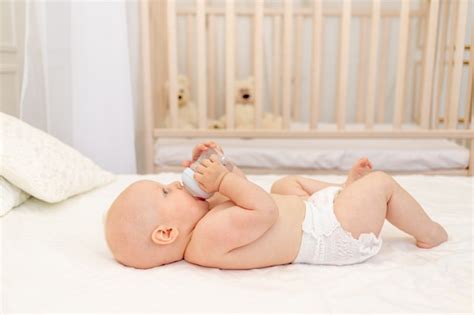 Baby boy 8 meses de edad acostado en pañales en una cama blanca con una