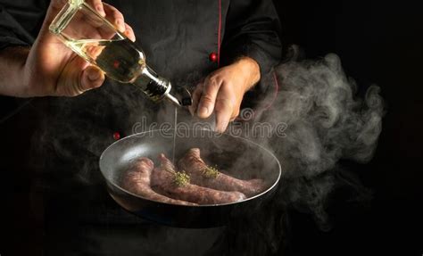 Professional Chef Adds Oil To Meat Sausages In A Steaming Hot Pan Place For Hotel Menu Or