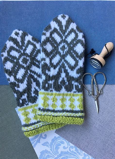 A Pair Of Mittens Sitting On Top Of A Table Next To A Pair Of Scissors