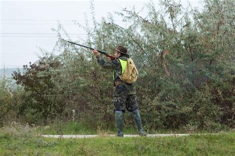 Chasseur en tenue de camouflage avec une arme à feu pendant la chasse à